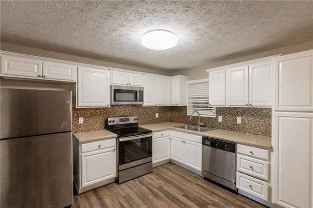 225 Fireside Way, Fairburn, GA 30213 - kitchen with appliances with stainless steel finishes, a sink, dark wood-style flooring, white cabinets, and a textured ceiling