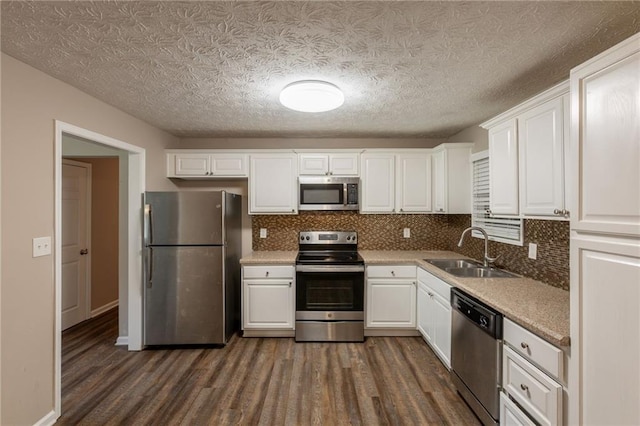 225 Fireside Way, Fairburn, GA 30213 - kitchen with appliances with stainless steel finishes, a sink, dark wood finished floors, white cabinets, and a textured ceiling