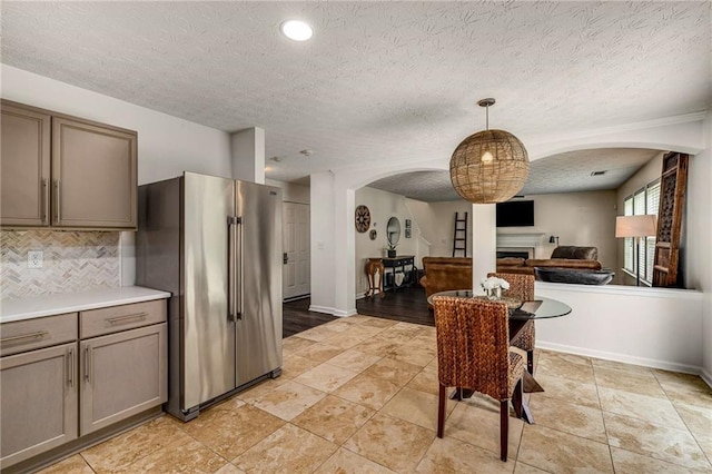 kitchen featuring a fireplace, arched walkways, open floor plan, tasteful backsplash, and high quality fridge