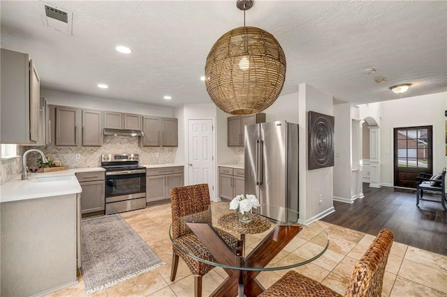 kitchen with visible vents, gray cabinetry, a sink, stainless steel appliances, and ornate columns