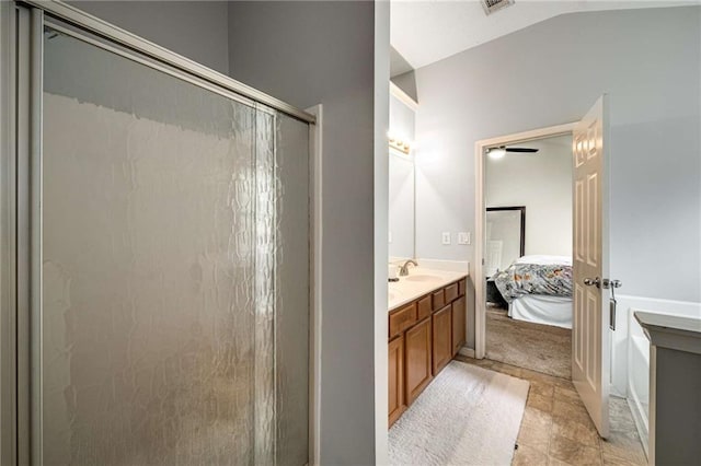 ensuite bathroom featuring stone finish floor, vaulted ceiling, a stall shower, vanity, and connected bathroom
