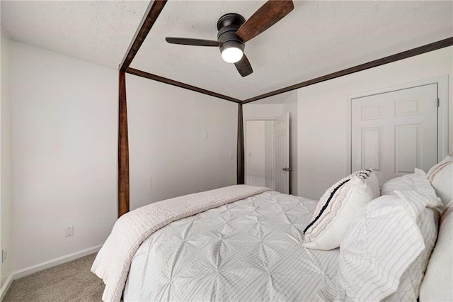 bedroom with light colored carpet, a textured ceiling, ceiling fan, and baseboards