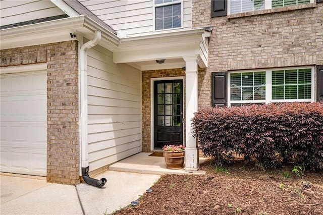 doorway to property with an attached garage and brick siding