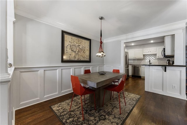 dining space with ornamental molding, dark wood-style flooring, a wainscoted wall, and a decorative wall