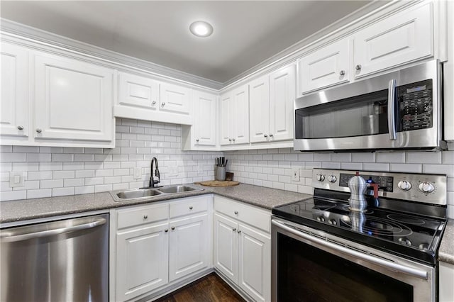 kitchen featuring tasteful backsplash, dark wood finished floors, appliances with stainless steel finishes, white cabinetry, and a sink