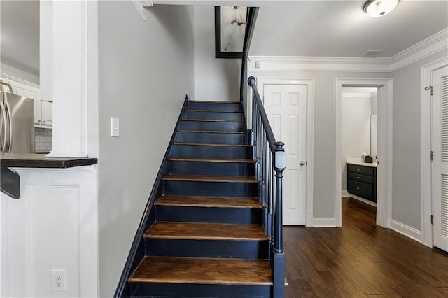 staircase featuring ornamental molding, wood finished floors, and baseboards