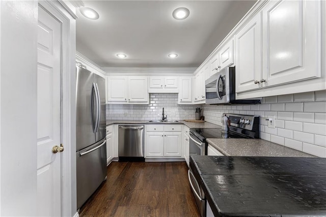 kitchen featuring stainless steel appliances, dark countertops, and white cabinetry