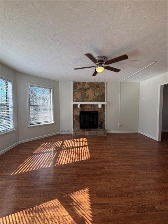 unfurnished living room with dark hardwood / wood-style flooring, ceiling fan, a fireplace, and a textured ceiling