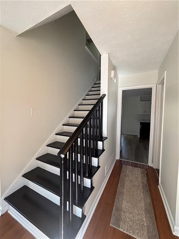 stairs with wood-type flooring and a textured ceiling