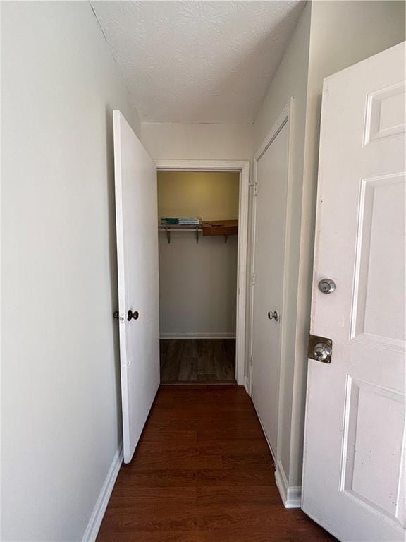 hall with dark wood-type flooring and a textured ceiling