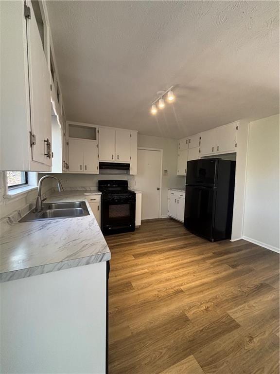 kitchen featuring sink, white cabinets, hardwood / wood-style flooring, black appliances, and a textured ceiling