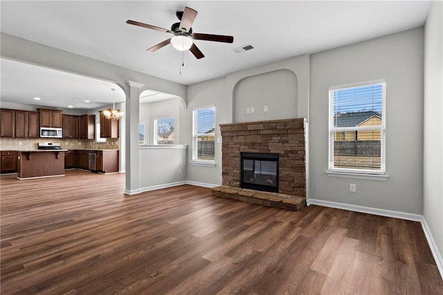 unfurnished living room with visible vents, a wealth of natural light, and dark wood-style floors