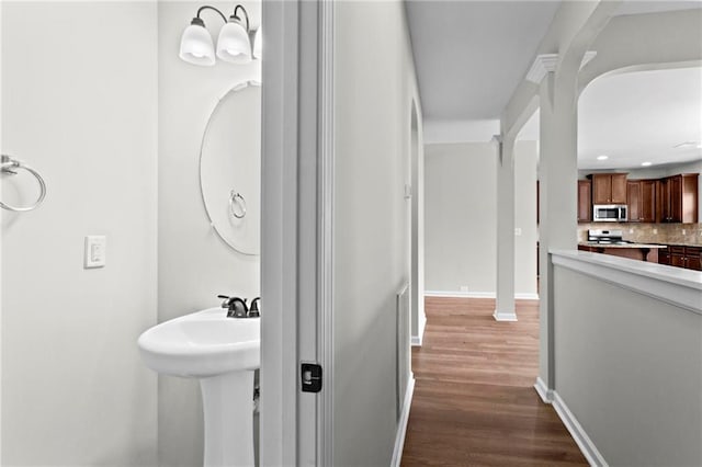 bathroom featuring recessed lighting, wood finished floors, a sink, baseboards, and backsplash