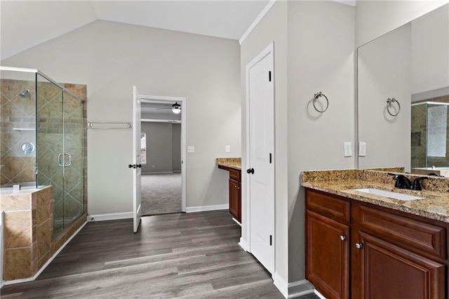 full bathroom featuring ceiling fan, a shower stall, vanity, vaulted ceiling, and wood finished floors