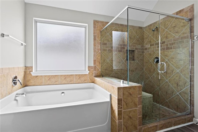 full bathroom with a shower stall, a bath, and plenty of natural light