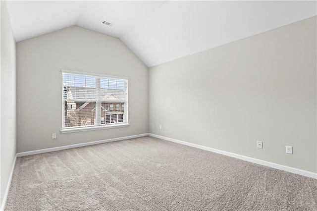 carpeted spare room with visible vents, baseboards, and vaulted ceiling
