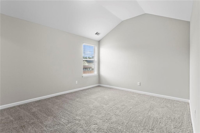 carpeted empty room featuring visible vents, baseboards, and lofted ceiling