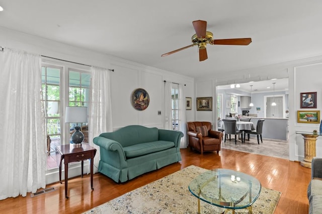 living area featuring ceiling fan, crown molding, and wood finished floors