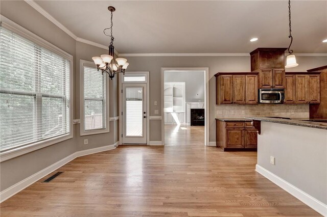 5195 Stefan Ridge Way, Buford, GA 30519 - kitchen featuring brown cabinets, plenty of natural light, an inviting chandelier, and stainless steel microwave