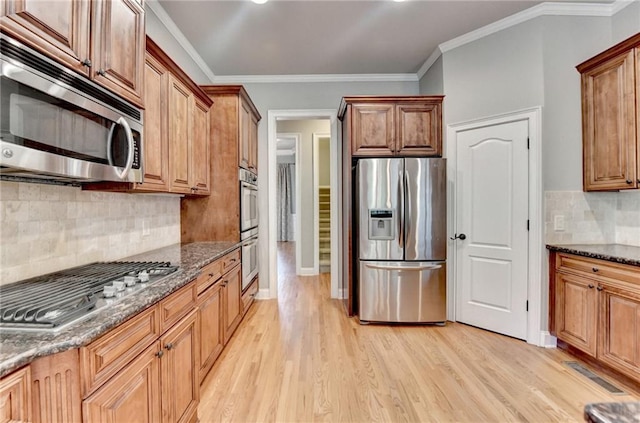 5195 Stefan Ridge Way, Buford, GA 30519 - kitchen with appliances with stainless steel finishes, crown molding, dark stone countertops, tasteful backsplash, and light wood-type flooring