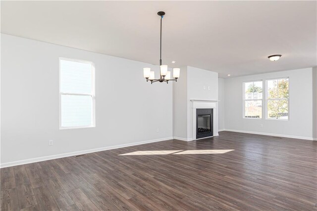 unfurnished living room featuring plenty of natural light and dark hardwood / wood-style floors