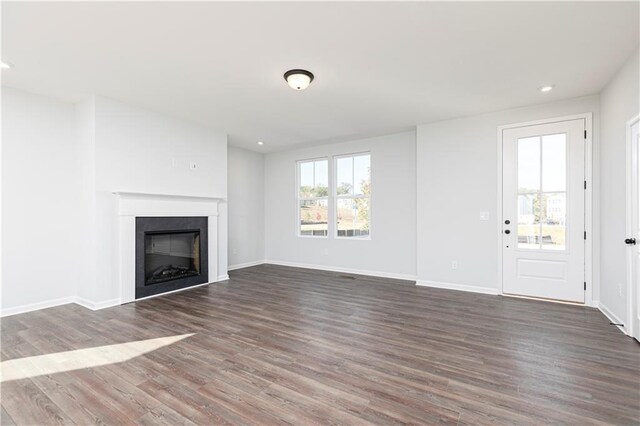 unfurnished living room with a healthy amount of sunlight, dark wood-type flooring, and a chandelier