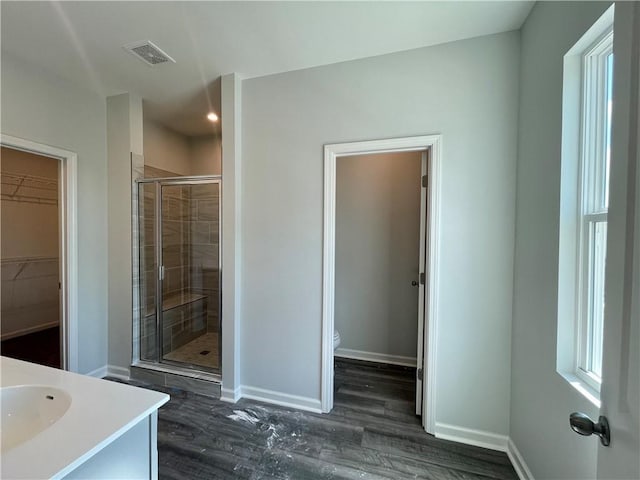 bathroom with hardwood / wood-style floors, vanity, toilet, and walk in shower