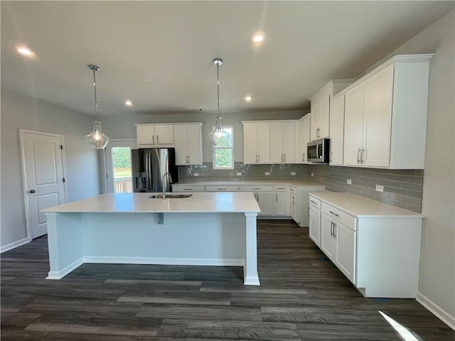 kitchen featuring white cabinets, an island with sink, pendant lighting, and appliances with stainless steel finishes