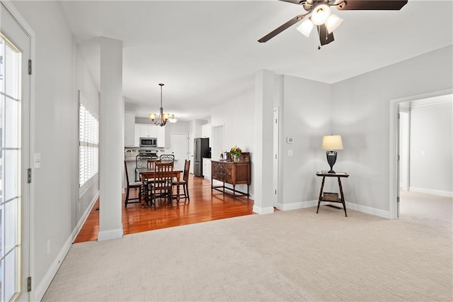 dining area with light colored carpet, baseboards, and ceiling fan with notable chandelier