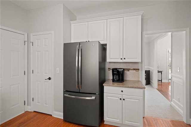 kitchen featuring freestanding refrigerator, white cabinets, and light wood-style flooring