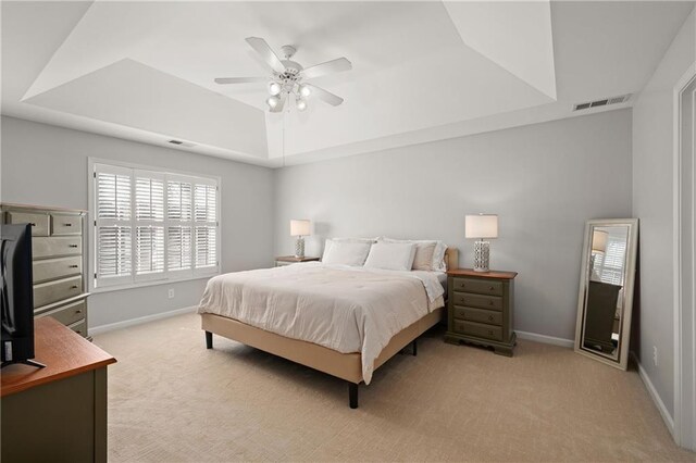 bedroom with light carpet, baseboards, visible vents, and a raised ceiling