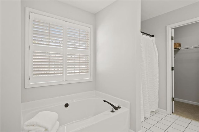 full bathroom featuring a spacious closet, tile patterned flooring, and a bath