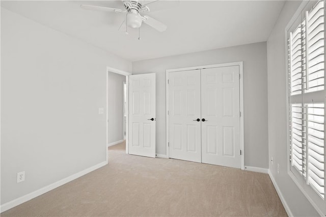 unfurnished bedroom featuring a closet, light carpet, ceiling fan, and baseboards