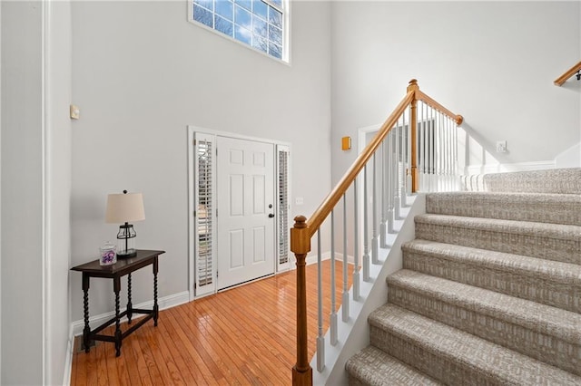 foyer with a high ceiling, stairway, wood finished floors, and baseboards