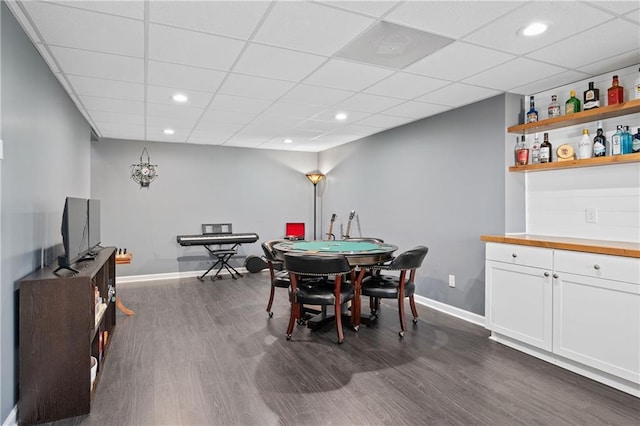 dining room with dark wood-type flooring, recessed lighting, a paneled ceiling, and baseboards