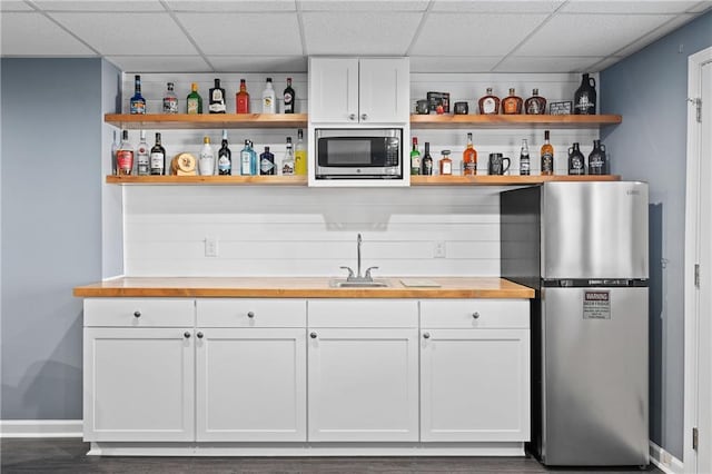 bar featuring a drop ceiling, appliances with stainless steel finishes, indoor wet bar, and a sink