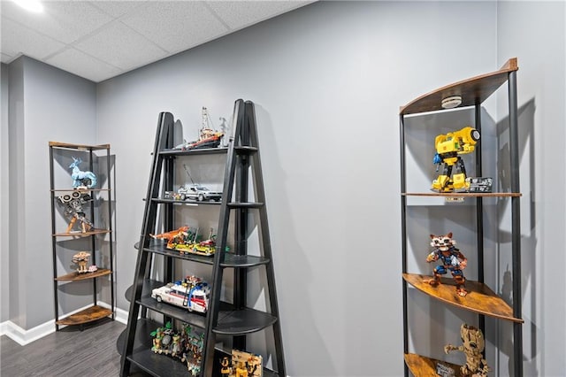 interior space featuring dark wood-type flooring, a drop ceiling, and baseboards