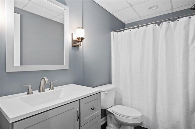 bathroom with toilet, a shower with shower curtain, vanity, and a paneled ceiling