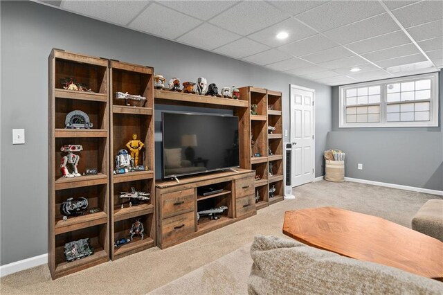 living area featuring a drop ceiling, light carpet, and baseboards