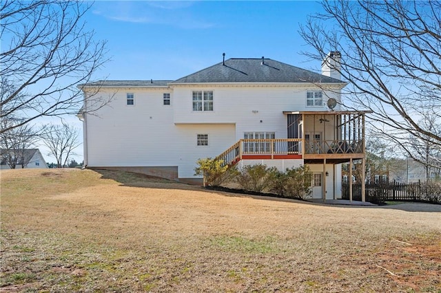 rear view of house featuring a yard, a chimney, a wooden deck, and stairs