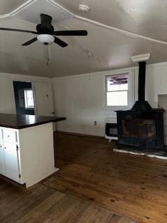 kitchen with ceiling fan, white cabinets, dark hardwood / wood-style flooring, vaulted ceiling, and a wood stove