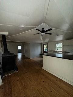 unfurnished living room with ceiling fan, lofted ceiling, dark hardwood / wood-style flooring, and a wood stove