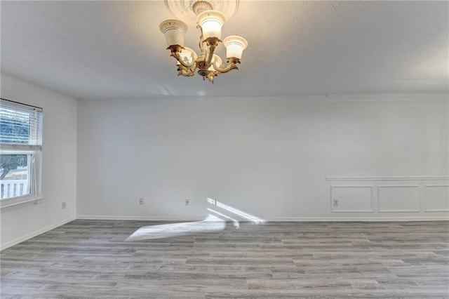 unfurnished room featuring an inviting chandelier and light hardwood / wood-style flooring