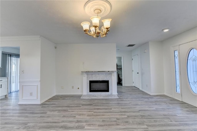 unfurnished living room with light hardwood / wood-style floors, a fireplace, and a chandelier