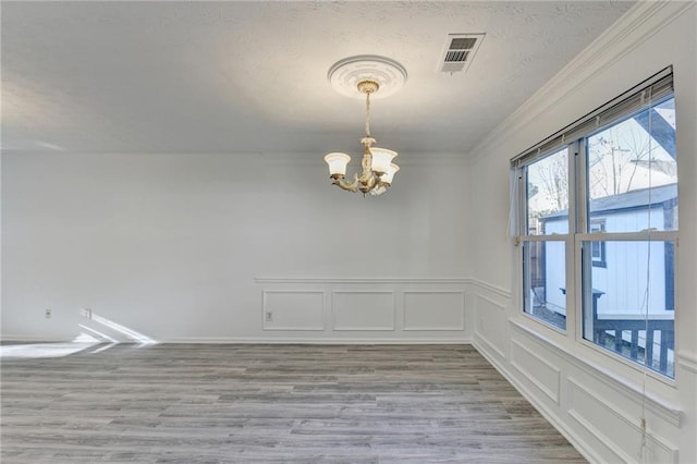 spare room featuring crown molding, an inviting chandelier, and light wood-type flooring