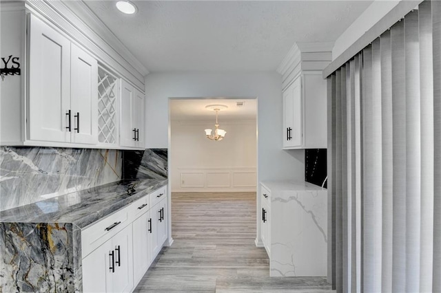 kitchen with dark stone countertops, white cabinetry, and light hardwood / wood-style flooring