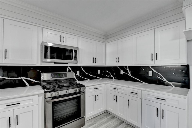 kitchen with light stone countertops, white cabinetry, stainless steel appliances, and tasteful backsplash