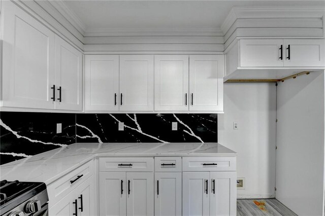 kitchen featuring light stone counters, crown molding, decorative backsplash, white cabinets, and light wood-type flooring