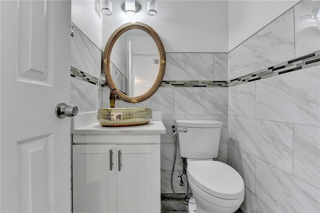 bathroom with vanity, toilet, and tile walls