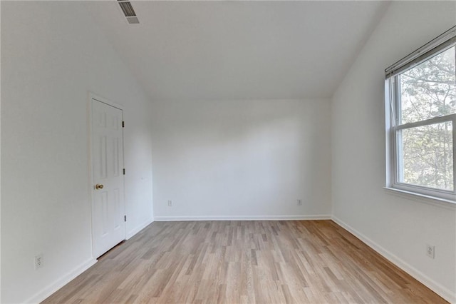 empty room with light hardwood / wood-style flooring, a wealth of natural light, and lofted ceiling